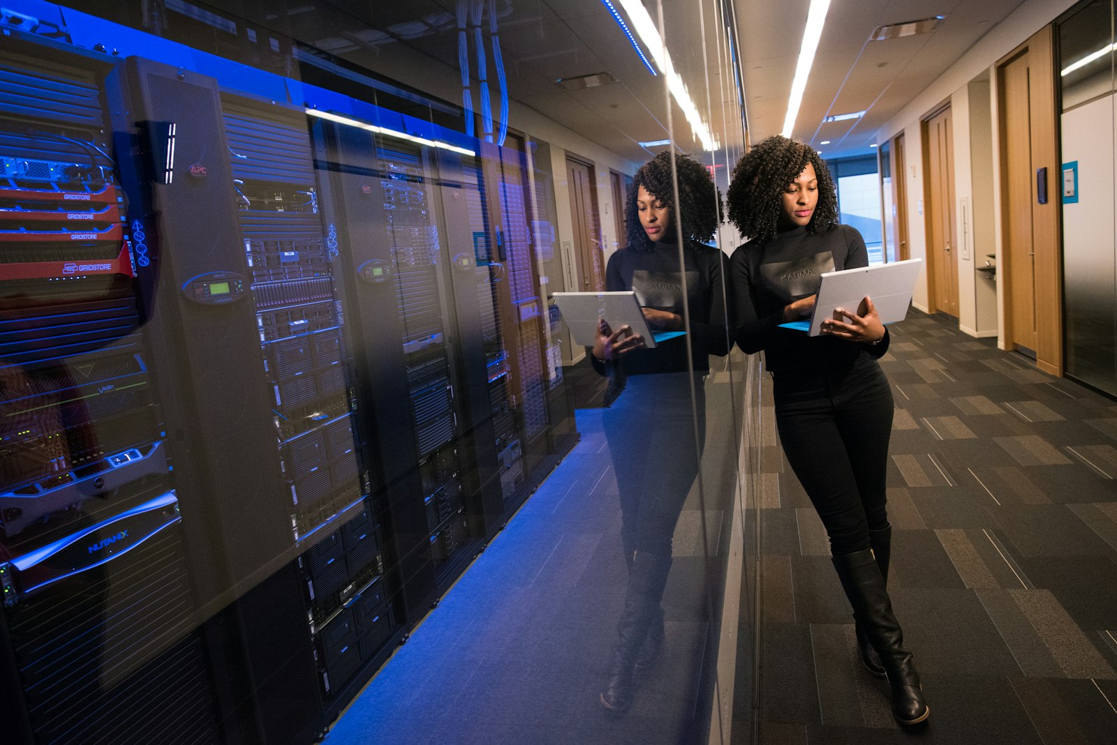 Engineers working with tablets in a data centre aisle lit by server racks