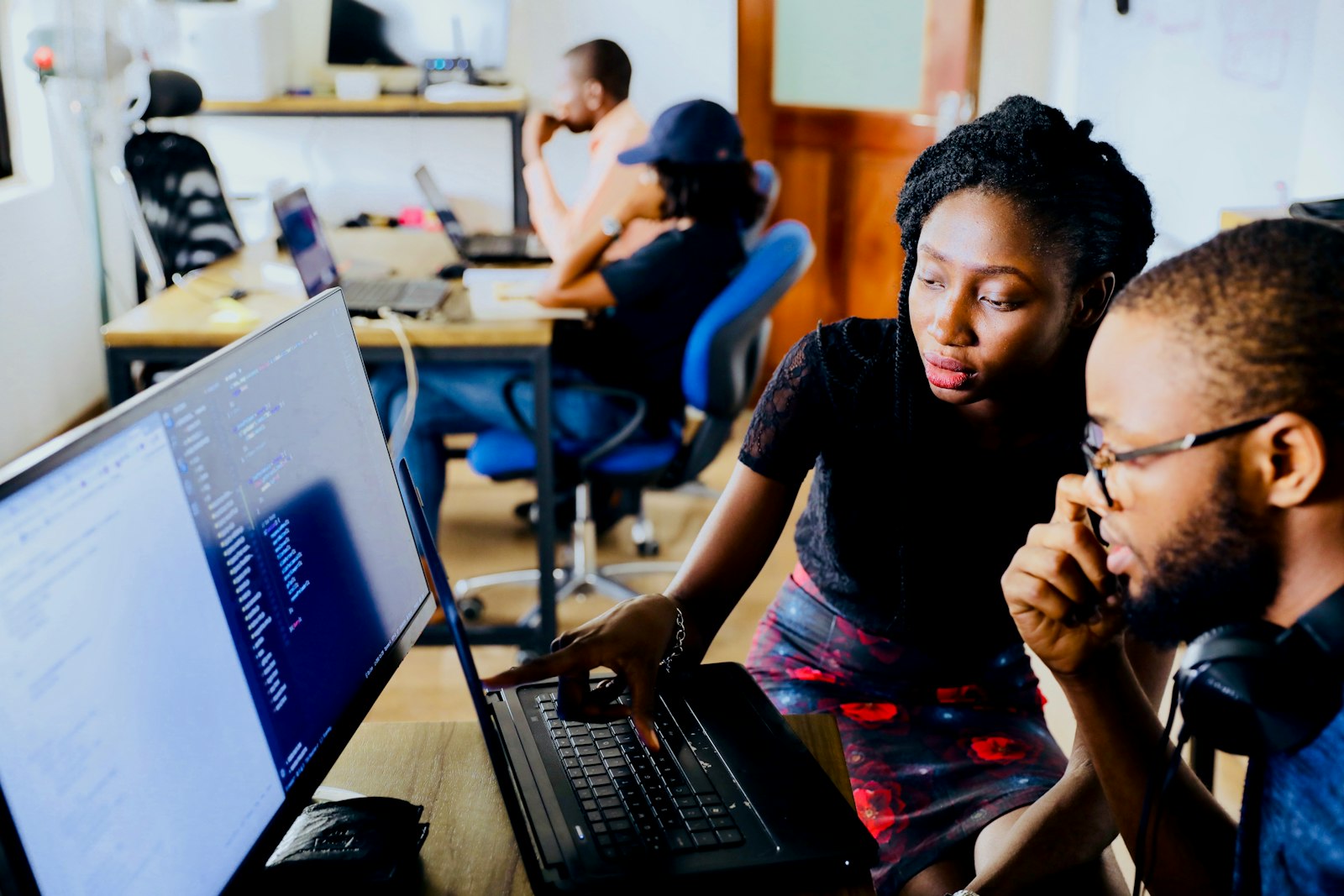 Two software engineers working through code together at a shared monitor