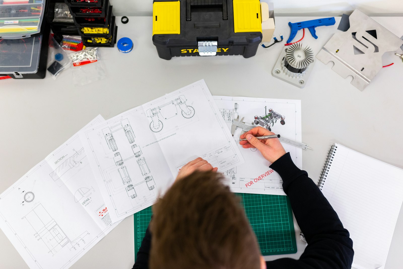 A designer working through product sketches and technical drawings at a desk