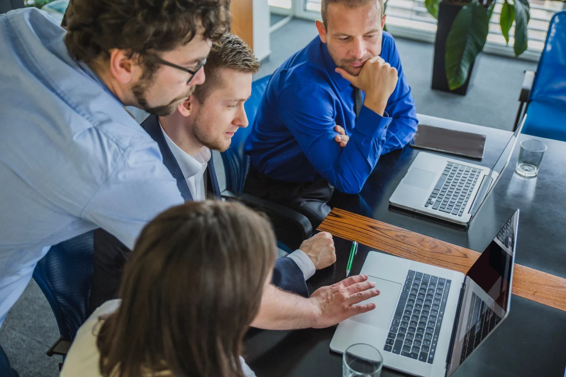Colleagues leaning in around a laptop to work through a problem together